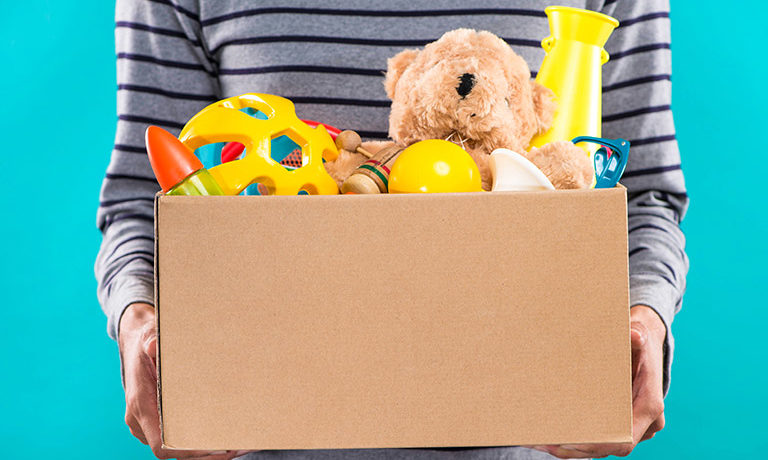 close-up view of a person holding a cardboard box of donated toys