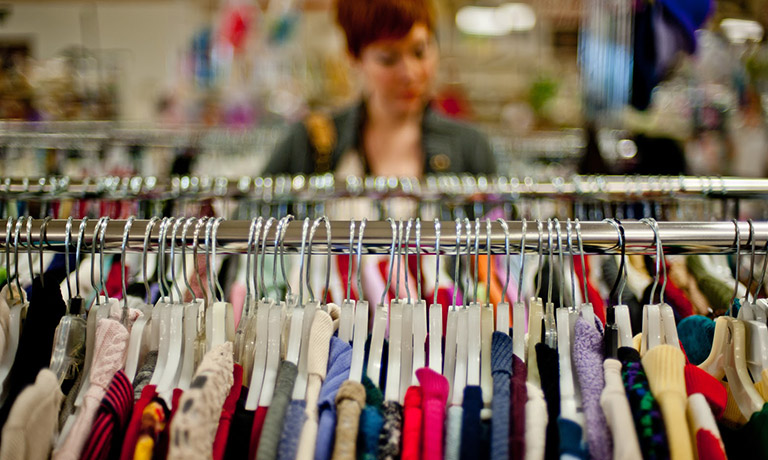 a woman browses the clothing racks at Goodwill