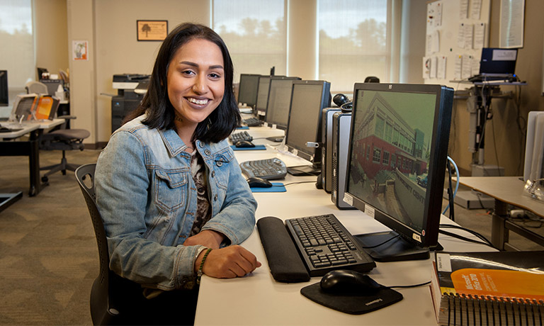 a young woman smiles for the camera in a computer lab