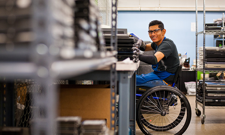 a young man in a wheelchair smiles while performing work task